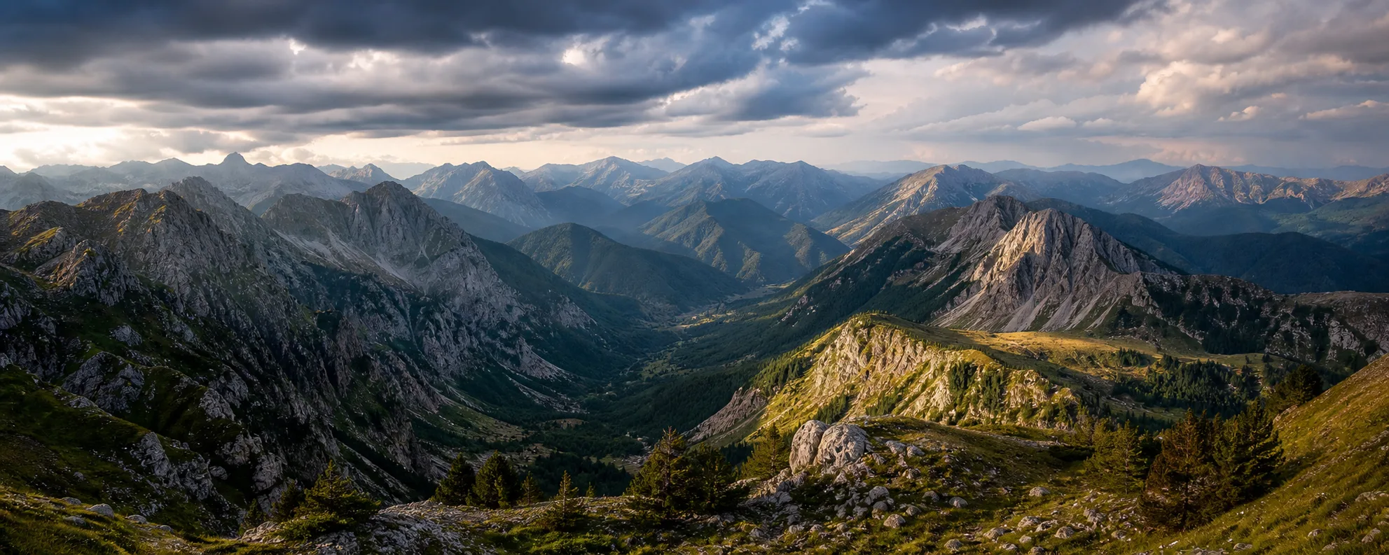 Panoramic mountain landscape with layered ridgelines, valleys, and changing weather.