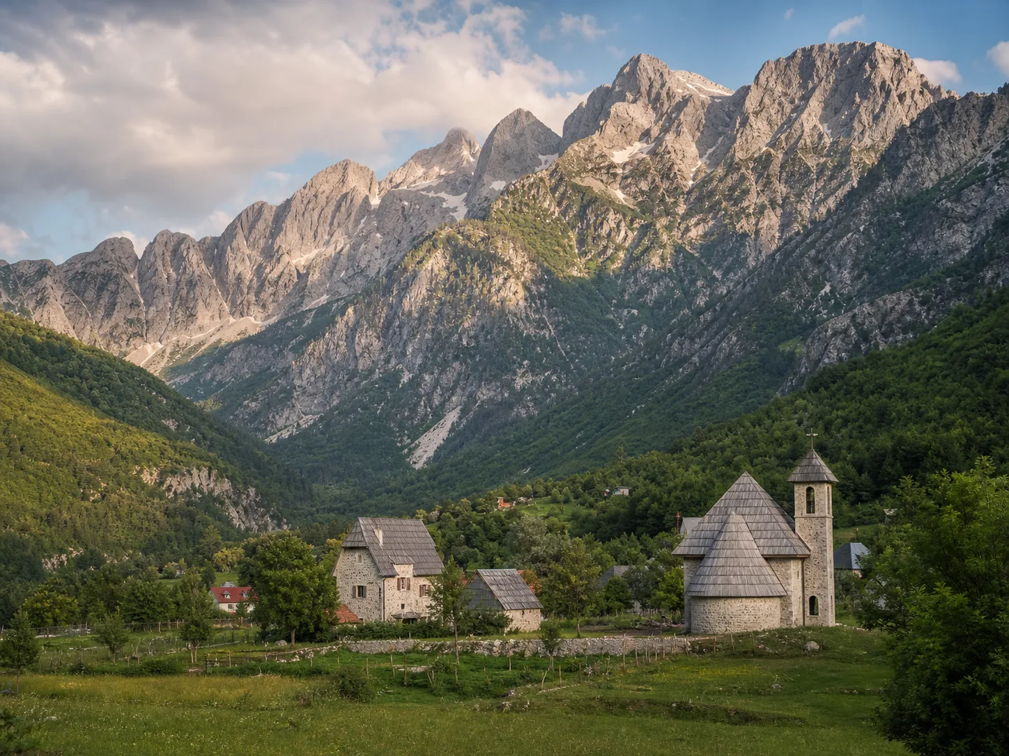 Remote mountain village with steep peaks and green valley light.