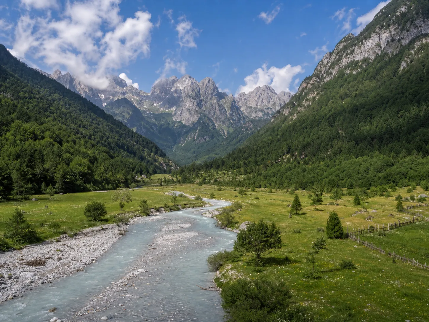 Wide mountain valley with a river cutting through alpine meadows.